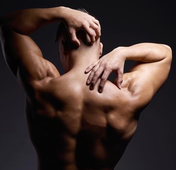 Do the work, the muscle will follow. Shot of a muscular young man posing against a black background.