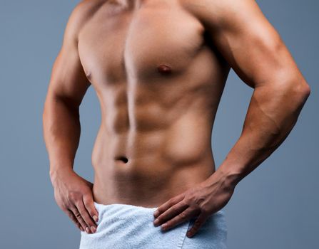 You cant downplay this body. Cropped shot of an unrecognizable man posing in a towel against a grey background.