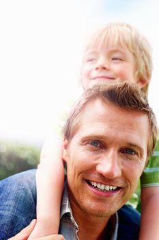 Smiling mature man giving his son piggyback ride. Closeup portrait of a smiling mature man giving his son piggyback ride.