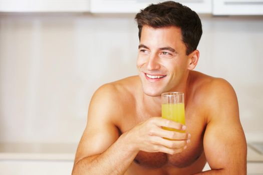 Muscular man with a glass of juice looking away - copyspace. A smiling muscular man with a glass of juice looking away - copyspace.