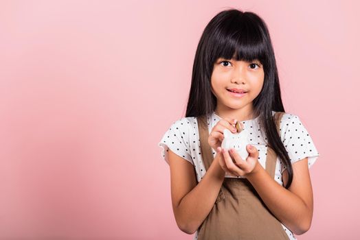 Asian little kid 10 years old holding piggy bank and looking at camera