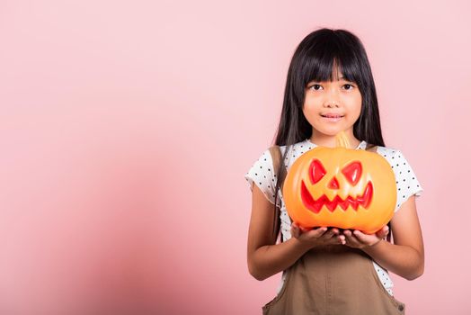 Asian little kid 10 years old holding carved Halloween pumpkin