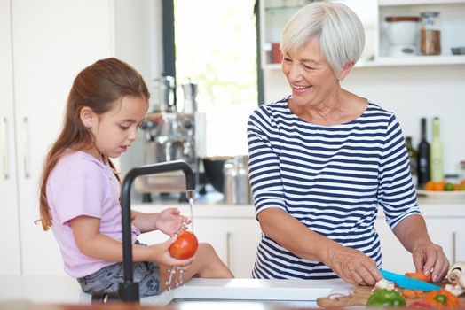 Youre a great little helper. Cropped shot of a grandmother washing vegetables with her grandchild in a kitchen.