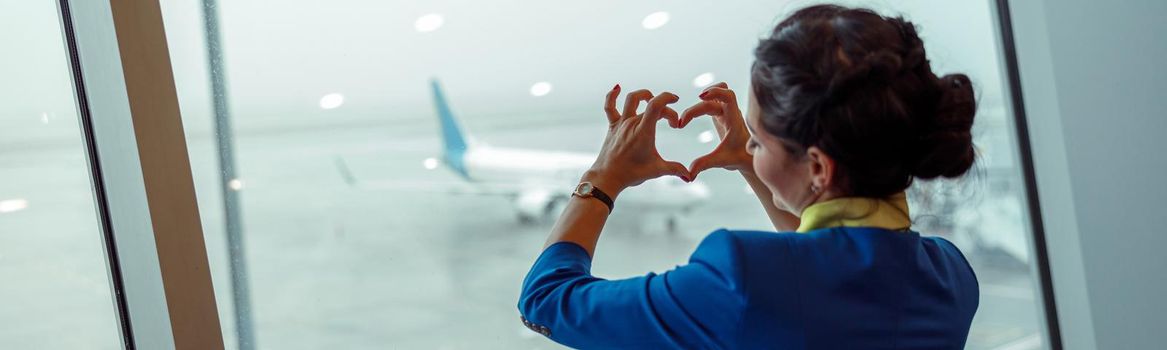 Woman stewardess doing heart symbol in airport terminal