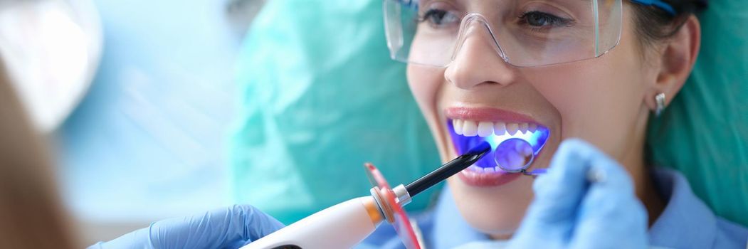 Dentist works with dental polymerization lamp in oral cavity