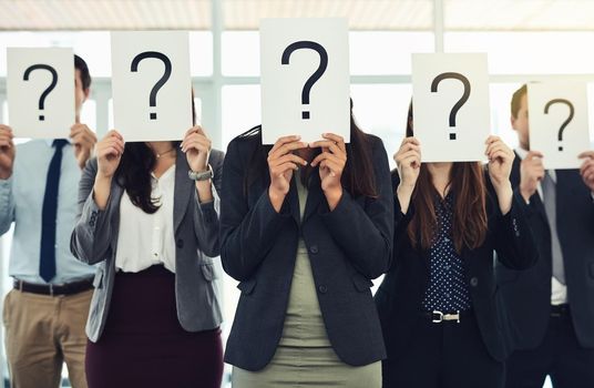 Do you have answers because we have questions. Shot of a group of businesspeople holding questions marks in front of their faces.