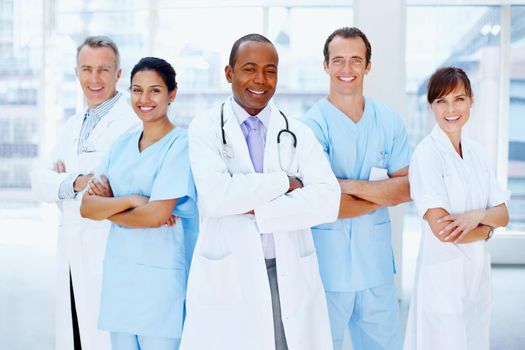 Doctor standing proud with his team. Doctor standing with his medical team.
