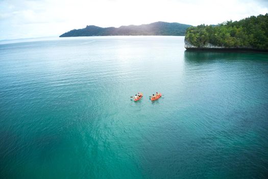 Were canoeing into the unknown together. High angle shot of two adventurous young couples canoeing together in the beautiful oceans of Indonesia.