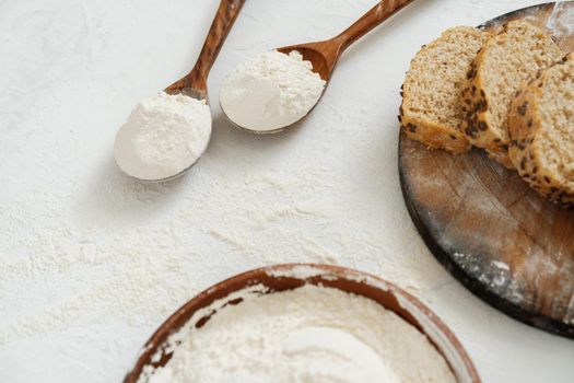 Pile of flour in wooden spoon on white background