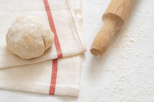 Rolling pin with dough on white background.