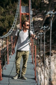 Portrait of middle-aged hiker passing by the hanging bridge and looking away. Travel concept