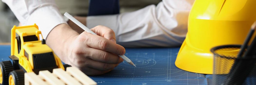 Male worker making corrections in construction planning with pencil