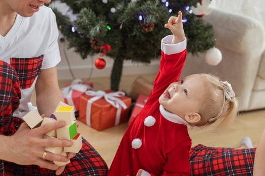 Baby child with hearing aid and cochlear implant having fun with parents in christmas room. Deaf , diversity and health and diversity