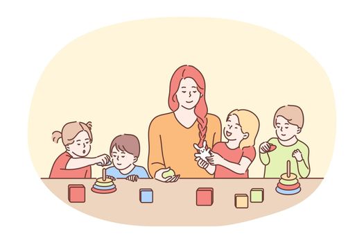 Nanny in kindergarten, babysitter, babysitting concept. Young smiling woman cartoon character babysitter or nanny playing with group of small children at table. Sister, mother, parenting