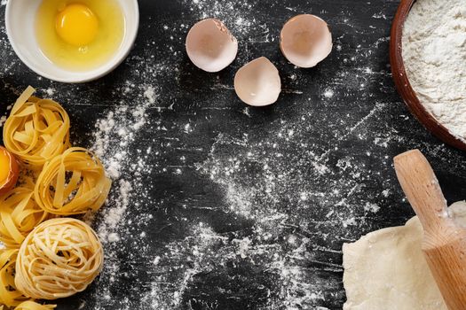 Raw egg pasta with flour on black background