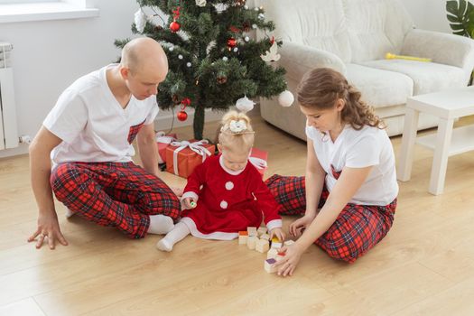 Baby child with hearing aid and cochlear implant having fun with parents in christmas room. Deaf , diversity and health and diversity