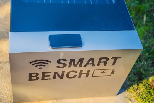 New smart bench in local public park used for charging mobile phones while providing wireless network