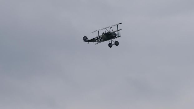Vintage biplane of First World War WWI in grey heavy rain cloudy sky. Copy space