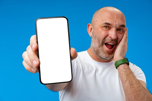 Middle-aged man showing blank smartphone screen with copy space against blue background