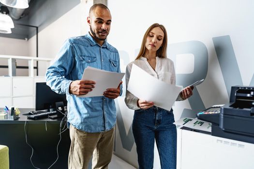 Two employees using new modern printer in office