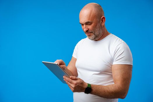 Handsome middle age man with digital tablet against blue background