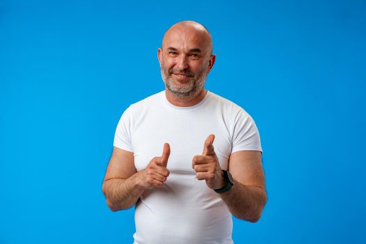 Handsome middle age senior man pointing at you over blue background