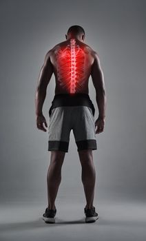 Bodybuilding can take a toll on your back. Rearview shot of an athletic young man with his back injury highlighted.