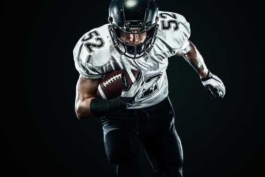 American football sportsman player in helmet isolated run in action on black background. Sport and motivation wallpaper.