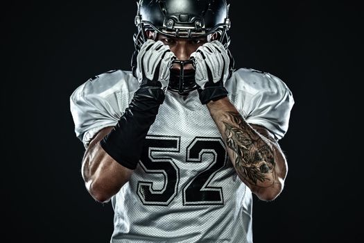 American football sportsman player in helmet isolated on black background. Sport and motivation wallpaper.