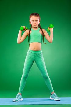 Kid girl doing fitness exercises on green background