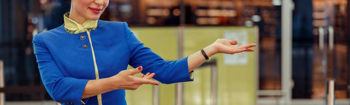 Joyful woman stewardess inviting to flight at airport