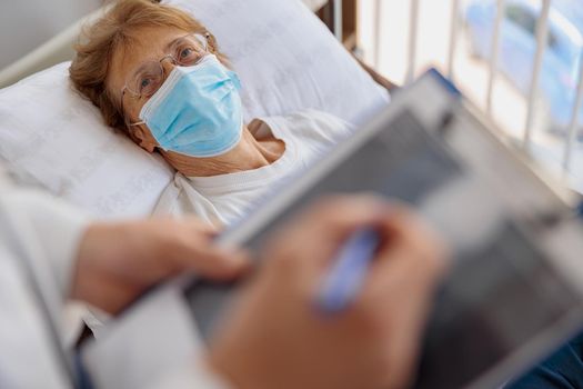Patient listens doctor's recommendations for treatment while lying in hospital ward