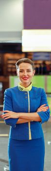 Joyful woman air hostess standing in airport terminal