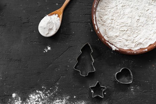 Pile of flour in wooden spoon on dark background