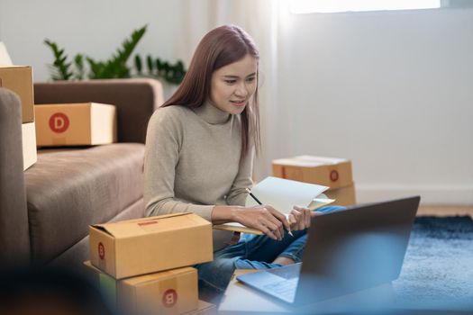 Asian woman Running Business From Home. Shipping shopping online, young start up small business owner packing cardboard box at workplace. Online selling or e-commerce