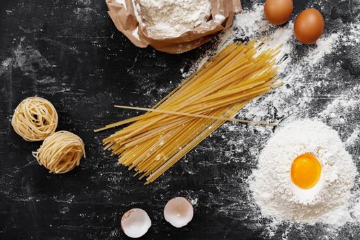 Raw egg pasta with flour on black background