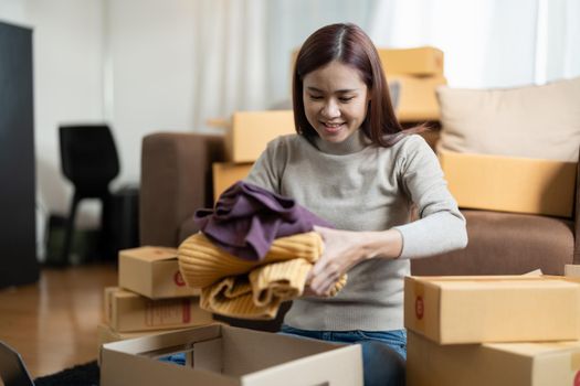 Asian female online store small business owner entrepreneur packing package post shipping box preparing delivery parcel on table. Ecommerce dropshipping shipment service concept.