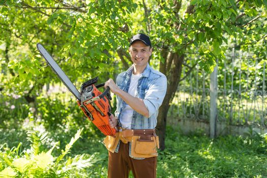 a man with a chainsaw. removes plantings in the garden from old trees, harvests firewood.