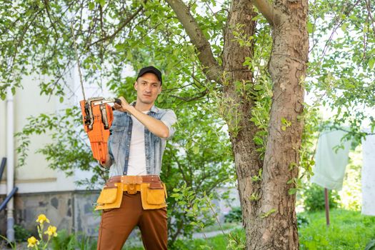 a man with a chainsaw. removes plantings in the garden from old trees, harvests firewood.