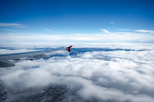Aircraft wing above beautiful clouds and blue sky