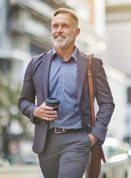 I can feel the caffeine in my veins. Shot of a handsome mature businessman walking around town drinking coffee.