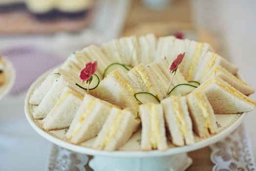 Small sandwiches make for perfect snacks. Shot of triangular sandwiches on a table at a tea party inside.