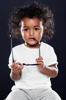 Hes such a cutie. Cropped shot of a cute girlholding spectacles on a black background.