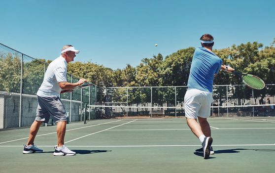 Work on that swing. Full length shot of a handsome mature sportsman coaching a fellow team-mate during a tennis training session.