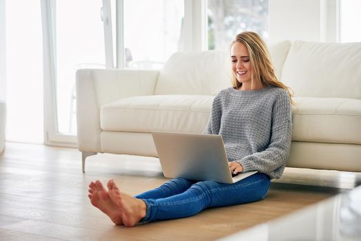 Finding a comfy place to blog. Full length shot of an attractive young woman using her laptop while chilling at home.