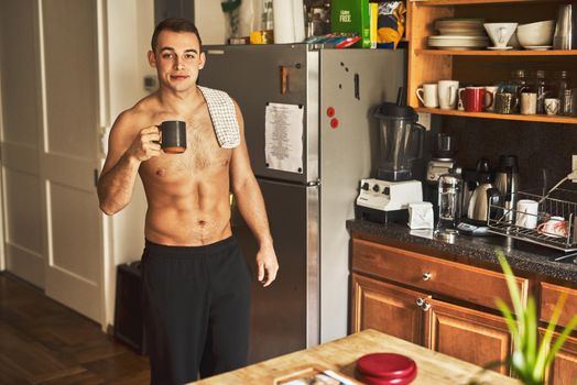 Coffee is the best thing to have in the morning. Cropped shot of a handsome young shirtless man drinking a cup of coffee in the kitchen at home.