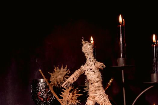Scary voodoo doll with black candles. Mystic background with ritual esoteric objects, occult and halloween concept.