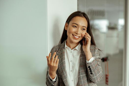 Asian business woman making a phone call and smiling standing at office