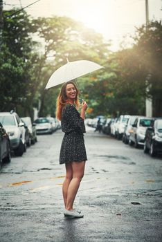Come rain or shine, she loves being outside. Shot of a beautiful young woman walking in the rain outside.