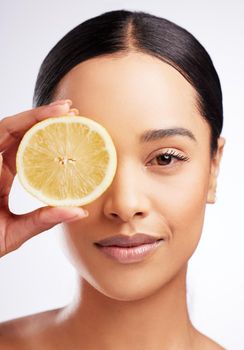 One ingredient that holds innumerable benefits. Studio portrait of a beautiful young woman posing with a lemon against a white background.